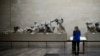 FILE - A woman looks at the Parthenon Marbles, a collection of stone objects, inscriptions and sculptures, also known as the Elgin Marbles, on show at the British Museum in London, Oct. 16, 2014.