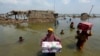 FILE — Women carry belongings after flooding in Sindh province, Pakistan, Sept. 6, 2022. Millions lost their homes in 2022 during floods that many experts blame on climate change. Countries moved closer Saturday to starting a fund to help poor states damaged by climate disasters.
