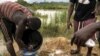 FILE - A group of illegal gold panners wash sand collected from a riverbed as they look for specks of gold, in Kibi area, southern Ghana, April 12, 2017.