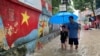 A man and a boy walk through a flooded street after heavy rains in Hanoi, Vietnam, Sept. 28, 2023.