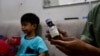 FILE - Riski Agri (R) displays a bottle of cough syrup that was consumed by his son Farrazka which caused him kidney problems, at their house in Jakarta, Indonesia, Feb. 11, 2023.