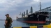FILE - A security officer stands next to the ship Navi-Star loaded with grain as it waits to sail to sail from the Odesa Sea Port, in Odesa, Ukraine, on July 29, 2022.