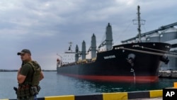 FILE - A security officer stands next to the ship Navi-Star loaded with grain as it waits to sail to sail from the Odesa Sea Port, in Odesa, Ukraine, on July 29, 2022.
