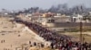 Palestinians wait for aid trucks to cross in central Gaza Strip on May 19, 2024. 