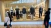 A window washer cleans the display window of a clothing store as shoppers pass by, at a mall in Lone Tree, Colorado, April 29, 2024.
