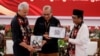 FILE - Ganjar Pranowo, presidential candidate of the ruling Indonesian Democratic Party-Struggle (PDI-P) and his running mate pass their registration documents to the Head of Indonesian Election Commission in Jakarta, Oct. 19, 2023.