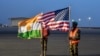 Wanajeshi wawili wa Niger wakishikilia bendera za Marekani na Niger kwenye kambi ya kijeshi mjini Niamey, wakati wa hafla ya kuondoka kwa kundi la kwanza la wanajeshi wa Marekani, Juni 7, 2024.