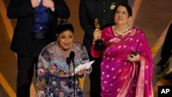 অ্যাকাডেমি অ্যাওয়ার্ডস-এর মঞ্চে ভারতে নির্মিত তথ্যচিত্র ‘দ্য এলিফ্যান্ট হুইস্পারার্স’ তথ্যচিত্রের পরিচালক কার্তিকী গনঞ্জালভেস ও প্রযোজক গুনিত মোঙ্গা।