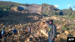 People gather at the site of a landslide in Maip Mulitaka in Papua New Guinea's Enga Province on May 24, 2024. Local officials and aid groups said a massive landslide struck a village in Papua New Guinea's highlands on May 24, with many feared dead. 