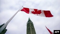 FILE - A Canadian flag flies in front of the peace tower on Parliament Hill in Ottawa, Canada on Dec. 4, 2015.