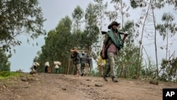 FILE — An unidentified armed militia fighter walks down a path as villagers flee, near the village of Chenna Teklehaymanot, Ethiopia, on Sept. 9, 2021. A human rights body reported on Dec.6, 2023, that more than 50 civilians were killed in attacks in Ethiopia in the past month.