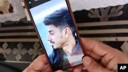 গ্রীক উপকূলে জাহাজডুবির পর নিখোঁজ পাকিস্তানের কাশ্মীরের কোটলির বিন্দিয়ান গ্রামের যুবক রাজা আওয়াইসের একটি ছবি সেল ফোনে ধরে রেখেছেন তার বাবা রাজা তারিক। ১৮ জুন, ২০২৩।