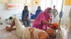FILE - A woman wipes the head of her ailing brother to keep him cool from the heat wave by using a wet cloth at the district hospital in Ballia, Uttar Pradesh state, India, June 19, 2023. 