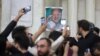 Poster yang menampilkan wajah presiden Iran yang baru terpilih, Masoud Pezeshkian, dibawa oleh pendukungnya ketika berkumpul di sebuah area di dekat Teheran, Iran, pada 6 Juli 2024. (Majid Asgaripour/West Asia News Agency via Reuters)