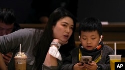 資料照 - 2023年1月19日北京一座咖啡館裡，一位母親正在和她孩子說話，而兒子卻目不轉睛地玩著手上的智能手機。