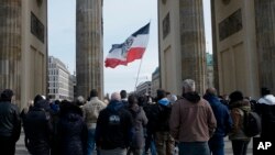 FILE - A flag in colors of the German Empire and with the Prussian heraldic eagle are displayed during a demonstration of right-wing extremists and and so called "Reich citizens" at the Brandenburg Gate in Berlin, Germany, March 20, 2021.