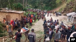 In this photo provided by the International Organization for Migration, an injured person is carried on a stretcher to seek medical assistance after a landslide in Yambali village, Papua New Guinea, May 24, 2024.