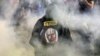 A protester wearing a garment depicting the Israeli prime minister walks through smoke as relatives and supporters of Israelis taken hostage by Palestinian militants in Gaza in the October 7 attacks demonstrate in Tel Aviv on May 26, 2024
