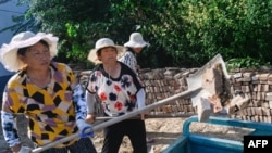 ผู้หญิงกลุ่มหนึ่งในเขตพิงหยวน ของมณฑลชานตง ประเทศจีน ซึ่งอยู่ใกล้จุดศูนย์กลางเหตุแผ่นดินไหวครั้งล่าสุด กำลังช่วยกันเก็บเศษอิฐที่หล่นมากองอยู่ตามพื้น เมื่อวันที่ 6 ส.ค. 2023 