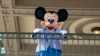FILE - An actor dressed as Mickey Mouse greets visitors at the entrance to Magic Kingdom Park at Walt Disney World Resort, April 18, 2022, in Lake Buena Vista, Fla. 