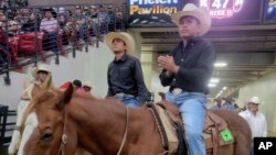 In this undated photo provided by Tyrone Tsosie, Tyrone Tsosie and his son, Tydon Tsosie, right, compete in the Indian National Finals Rodeo in Las Vegas.