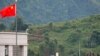 FILE - Myanmar government troops stand on a rooftop on the Myanmar side, near a Chinese flag from the Chinese border town of Nansan in southwestern China's Yunnan province, Aug 30, 2009. 