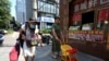 An elderly woman walks by a store selling snacks in Beijing, July 17, 2023. 