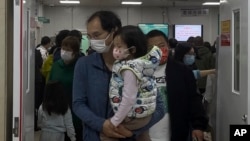 FILE - A man with a child walks out from a crowded holding room of a children's hospital in Beijing on Oct. 30, 2023.