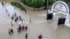Pedestrians wade through a flooded street following heavy rains at Kiembeni district in Mombasa, Kenya, Nov. 17, 2023. 
