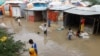 Somali children wade through flood waters outside their makeshift shelters following heavy rains at the Al Hidaya camp for the internally displaced people on the outskirts of Mogadishu, Somalia, Nov. 6, 2023. 