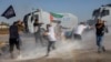 Protestors hold a Palestinian flag as Turkish anti-riot police uses water cannons to disperse them during a Pro-Palestinian demonstration against US secretary of state's visit to Turkey near the Incirlik Air Base, southern Turkey, Nov. 5, 2023. 