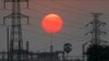 FILE - The sun sets behind electricity pylons in Krang Tnung village on the outskirts of Phnom Penh, Cambodia, Dec. 26, 2019.