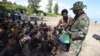 An Indonesian soldier inspects the identification of ethnic Rohingya men after they land on a beach in Pidie, Aceh province, Indonesia, Dec. 10, 2023. 