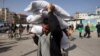 FILE — A man carries bags of humanitarian aid in Rafah in the southern Gaza Strip, Nov. 26, 2023. The United States on Tuesday sent the first of three military planes to Egypt with humanitarian aid for Gaza.
