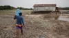 A man carries a bottle of water in a dry area of the Igarape do Taruma stream which flows into the Rio Negro River, in Manaus, Brazil, Oct. 16, 2023. 