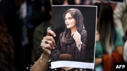 FILE - A protester holds a portrait of Mahsa Amini during a demonstration in her support in front of the Iranian embassy in Brussels, Belgium, Sept. 23, 2022, following the death of Amini after her arrest by the country's morality police in Tehran.