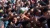 Migrants rise their hands to get some food and water distributed by Caritas on the Greek-FYR Macedonia border near the vilage of Idomeni, Sept. 5, 2015.