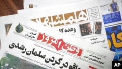 The front pages of the Aug. 13 edition of the Iranian newspapers, Vatan-e Emrooz, front, with the headline 'Knife in the neck of Salman Rushdie,' and Hamshahri, rear, with the headline: 'Attack on writer of Satanic Verses,' are pictured in Tehran, Aug. 13, 2022.