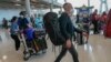 FILE - Tourists arrive at Suvarnabhumi International Airport in Bangkok, Thailand, Monday, Nov. 1, 2021. Thailand announced Friday, April 22, 2022, that visitors who are fully vaccinated against the coronavirus will no longer need to undergo any test or q