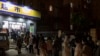 Residents wearing face masks to help protect from the coronavirus line up outside a supermarket at night to buy groceries, March 27, 2022, in Shanghai, China. 