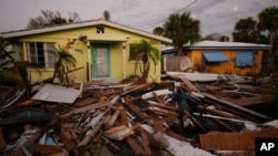 FILE - Debris from homes destroyed by Hurricane Milton lies strewn around still-standing houses on Manasota Key, Florida, Oct. 12, 2024.