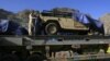 A man stands atop of a truck, carrying supplies for NATO Forces, as he covers a vehicle with plastic sheet before he departed for Afghanistan through the Pakistan-Afghan border town of Torkham October 10, 2010. Pakistani authorities on Sunday reopened a b