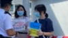 兩名香港大專女學生化名阿貓(左）及H同學，4月11日在尖沙咀天星碼頭五支旗桿下，手持聲援烏克蘭的標語進行”快閃”反戰示威，被警員截查，警告她們可能違反防疫”限聚令”。 (美國之音/湯惠芸) 