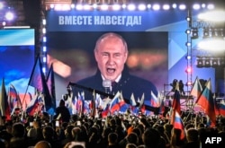 Rais wa Russia Vladimir Putin akihutubia kupitia luninga katika uwanja wa Red Square, huku watu wamekusanyika katika maadhimisho ya kuingizwa mikoa ya Ukraine katika himaya ya Russia, huko Moscow Sept. 30, 2022.