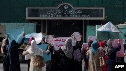 Afghan women hold placards as they take part in a protest in front of the Iranian embassy in Kabul, Sept. 29, 2022.
