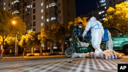 上海封城後，一名快遞員將食物袋送到一個住宅小區大門外。（2022年4月11日）