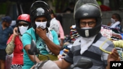 Waendesha pikipiki wakivalia vifaa vya kujilinda na Covid-19, wakipita ndani ya soko la New Delhi Agosti 30, 2020.