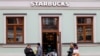 FILE - People wait for their orders outside a Starbucks coffee shop in Moscow, Russia, Oct. 29, 2021.