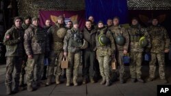 Nan foto sa a ke Biwo Prezidans Ikren nan pataje ak lapres, solda Ikrenyen yo poze pou yon foto ak Prezidan Volodymyr Zelenskyy (mitan) pandan yon vizit li te fe nan Sloviansk, rejyon Donbas, Ikren, 6 Desanm, 2022. 
