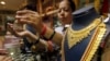 FILE - A saleswoman shows a gold earring to customers at a showroom in Mumbai, India.
